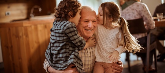 Ein Großvater der von seinen Enkelkindern einen Kuss bekommt.