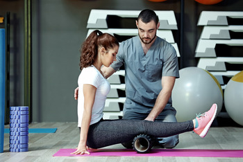 Therapeut macht Fitnessübungen mit einer Frau